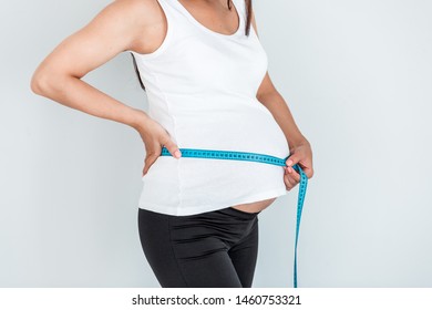 Pregnant woman measures her tummy by tape measure - isolated on pale blue background. - Shutterstock ID 1460753321