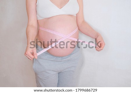 A pregnant woman is measuring her belly. Overweight concept.