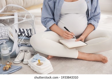 Pregnant woman packing bag for maternity hospital at home, closeup