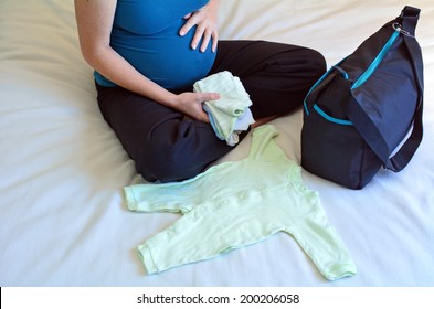 Pregnant Woman Packing A Hospital Bag. Pregnancy Concept Lifestyle And Health Care. Real People. Copy Space