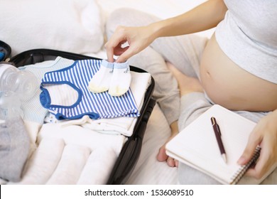 Pregnant woman packing suitcase go hospital, Check list and Preparing baby clothing getting ready for newborn birth necessities.                               