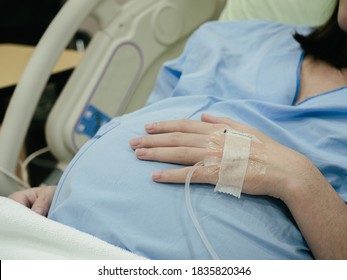 Pregnant Woman patient is waiting to deliver baby with drip receiving a saline solution on bed at hospital, selective focus. Health Care concept, insurance concept, mother concept - Powered by Shutterstock