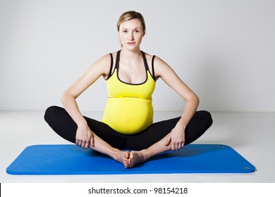 Pregnant Woman Performing An Inner Thigh Leg Stretch On A Mat