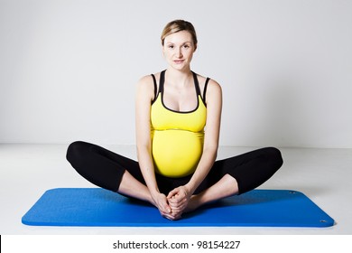 Pregnant Woman Performing An Inner Thigh Leg Stretch On A Mat