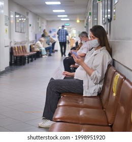 Pregnant woman with phone in hospital corridor with medical mask on face - Moscow, Russia, May 16, 2021 - Powered by Shutterstock