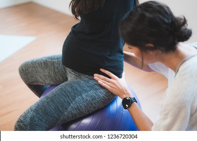 Pregnant woman pilates exercise workout at gym with personal trainer. Happy future mother doing pilates exercises