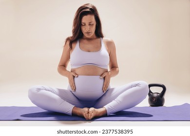 Pregnant woman practicing prenatal yoga in a studio, focusing on breathing and meditation. Expecting mom performing the butterfly pose on an exercise mat, caring for her belly in the third trimester. - Powered by Shutterstock