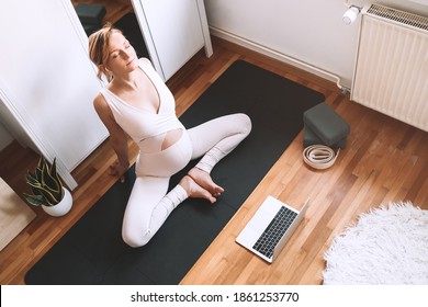 Pregnant Woman Practicing Yoga At Home With Laptop. Expectant Mother Doing Prenatal Video Training Class Indoors. Female Exercise, Meditate During Pregnancy. Online Fitness Class On Digital Devices.