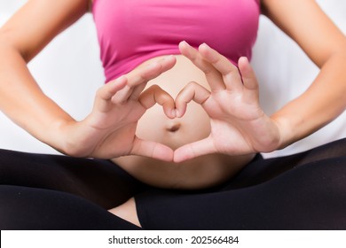 Pregnant Woman Pregnancy Concept Heart On Stomach. Hands Forming Heart On Female Belly Button. Healthy Stomach Health Concept, Or Early Pregnancy Concept With Beautiful Female Hands.