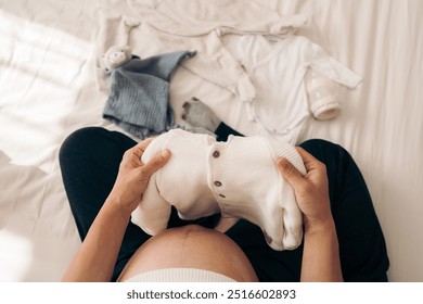 Pregnant woman preparing baby's clothes at home - Powered by Shutterstock