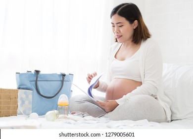 Pregnant Woman Preparing Hospital Bag Checklist And Making A Birth Plan From A Hospital That Has Antenatal Care For Safety Of The Baby, Planning Prenatal Concept