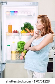 schwangere Frau und Kühlschrank mit gesundem Gemüse und Obst