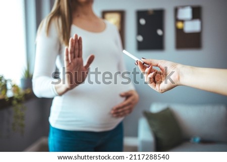 Pregnant woman refusing a cigarette. Pregnant Woman Gesturing Stop Refusing Take Cigarette Standing at home. Pregnancy And Smoking.