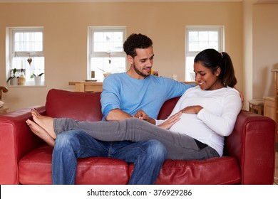 Pregnant Woman Relaxes On Sofa With Husband - Powered by Shutterstock