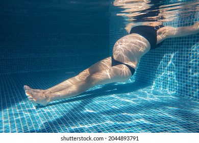 pregnant woman relaxes in a pool of blue water. Unrecognizable body. 