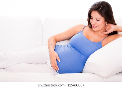 Pregnant woman relaxing at home looking very happy