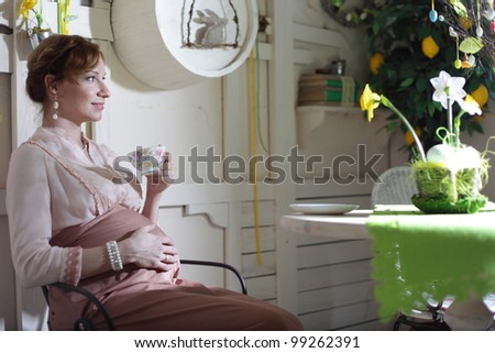 Pregnant woman sitting with cup