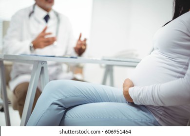 Pregnant Woman Sitting With Doctor At Clinic For Health Checkup