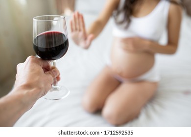 Pregnant woman is sitting on the bad and she is offered to drink a glass of the red wine but she refuses. The danger and harm of alcohol to pregnant woman 
