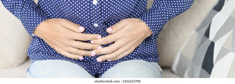 Pregnant Woman Is Sitting On Couch And Holding Belly. Pain In Lower Abdomen In Women Concept