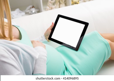 Pregnant woman sitting on sofa and using blank screen tablet