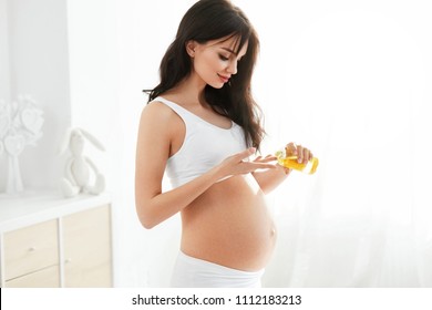 Pregnant Woman Skin Care. Female Applying Oil On Belly