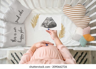 Pregnant woman with sonogram image near baby crib - Powered by Shutterstock