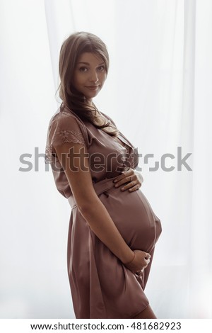 Pregnant woman standing against the window
