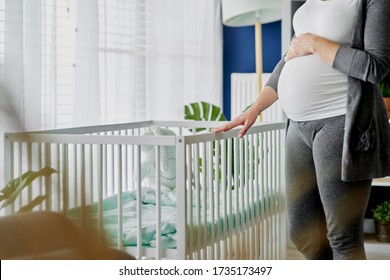 Pregnant Woman Standing Next To A Crib