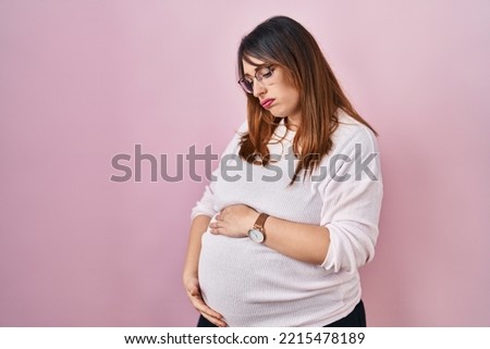 Pregnant woman standing over pink background looking sleepy and tired, exhausted for fatigue and hangover, lazy eyes in the morning. 