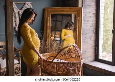 pregnant woman stands by a wicker cradle. Baby bassinet made of natural wooden materials. Eco parenting. Baby cot preparation for birth of a child. Stylish modern boho interior. Waiting for childbirth - Powered by Shutterstock