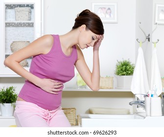 Pregnant Woman With Strong Pain Of Stomach And Nausea Sitting In Bathroom