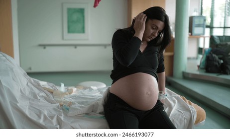 Pregnant woman suffering from contractions during pre labor at clinic covering face in pain, expecting mother at hospital waiting for childbirth - Powered by Shutterstock