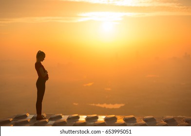 Pregnant woman sunset silhouette on top of a high-rise. 