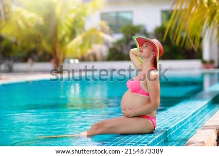 Pregnant woman in swimming pool. Healthy and active pregnancy.  Young expecting mom on tropical vacation before baby birth. Swim holiday and water fun. Expectant mother relaxing in exotic resort.