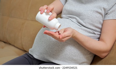 Pregnant woman takes care of future baby in bump and own health and uses pills. Gravid lady takes vitamins in pills to be wellbeing and have healthy baby