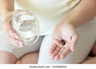 Pregnant Woman Takes Food Supplement Vitamins Calcium Vitamin C Or Aspirin.hand With Glass Full Filed With Water And Capsule In Another,white Round Pills Tablets.fenale In Last Trimester Of Pregnancy,