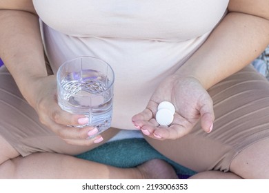 Pregnant Woman Takes Food Supplement Vitamins Calcium Vitamin C Or Aspirin.hand With Glass Full Filed With Water And Capsule In Another,white Round Pills Tablets.fenale In Last Trimester Of Pregnancy,