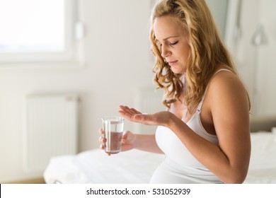 Pregnant Woman Taking Pill Against Heartburn