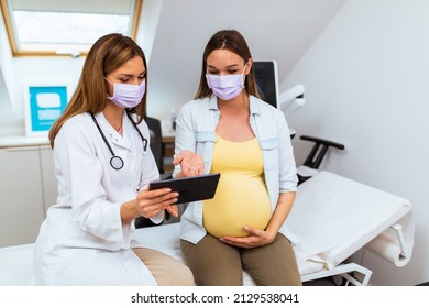 Pregnant woman is talking with her doctor at clinic. The doctor and the pregnant woman are wearing protective face masks due to the coronavirus pandemic. - Powered by Shutterstock