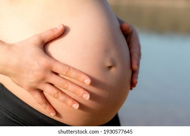 A pregnant woman touching her belly with her hands carefully