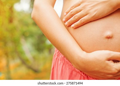 pregnant woman touching her naked abdomen