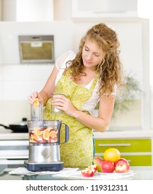 Pregnant Woman Using A Juicer, Standing In The Kitchen