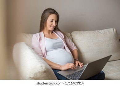 Pregnant woman using laptop on the sofa - Powered by Shutterstock