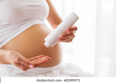 Pregnant woman using moisturizer 