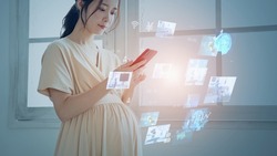 Pregnant woman using a smart phone. Obstetrics and gynecology. Femtech., a Technology Photo by metamorworks
