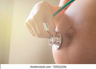 Pregnant woman using stethoscope on belly - Shutterstock ID 723216196