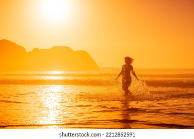 Pregnant woman walking on ocean beach at beach with sunrise or sunset tones - Powered by Shutterstock