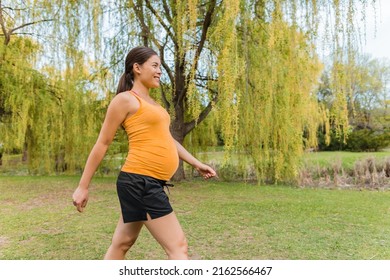 Pregnant Woman Walking Outside In City Park During Summer For Healthy Active Body Workout. Cardio Walk During Pregnancy