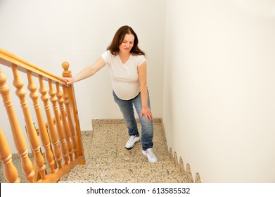 Pregnant Woman Walking Up The Stairs At Home And Touching His Knee By The Pain